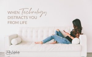When Technology Distracts You from Life | woman in blue jeans and black shirt sitting across couch holding phone in hands, looking at phone
