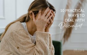 10 Practical Ways to Deal With Discomfort | woman in tan sweater sitting down with head in hands